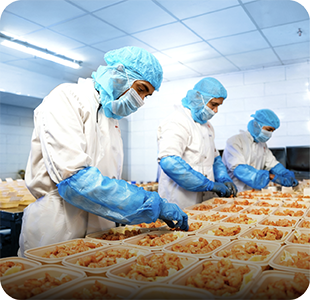 Chefs portioning chicken into meal trays