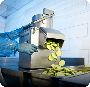 A chef slicing courgettes with a commercial food processor